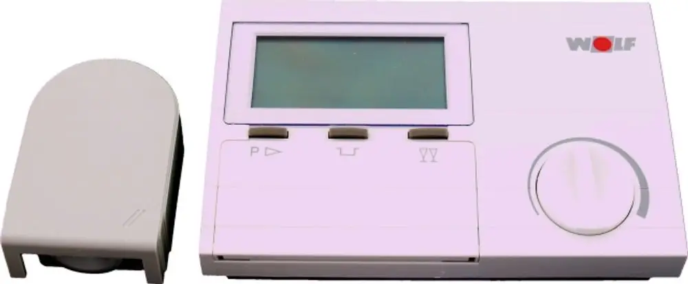 Digitaler Temperaturregler von Wolf mit Display und Steuerknopf. Zubehörteil auf der linken Seite. Gerät in neutraler Farbgebung, geeignet für Steuerungsanwendungen.